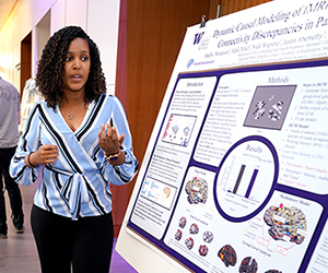 A young woman standing in front of a research poster